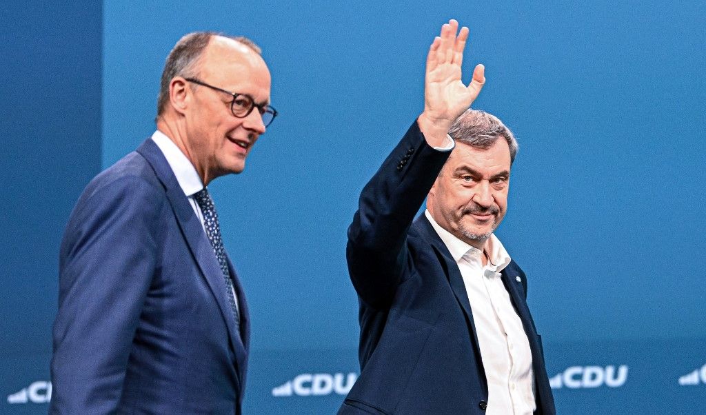 Bavaria's State Premier and leader of the conservative Christian Social Union (CSU) Markus Soeder greets the delegates next to German Chancellor and leader of Germany's Christian Democratic Union (CDU) Friedrich Merz as he arrives at the party congress of the Christian Democratic Party (CDU) at the fair grounds in Stuttgart, southern Germany, on February 21, 2026. (Photo by THOMAS KIENZLE / AFP)