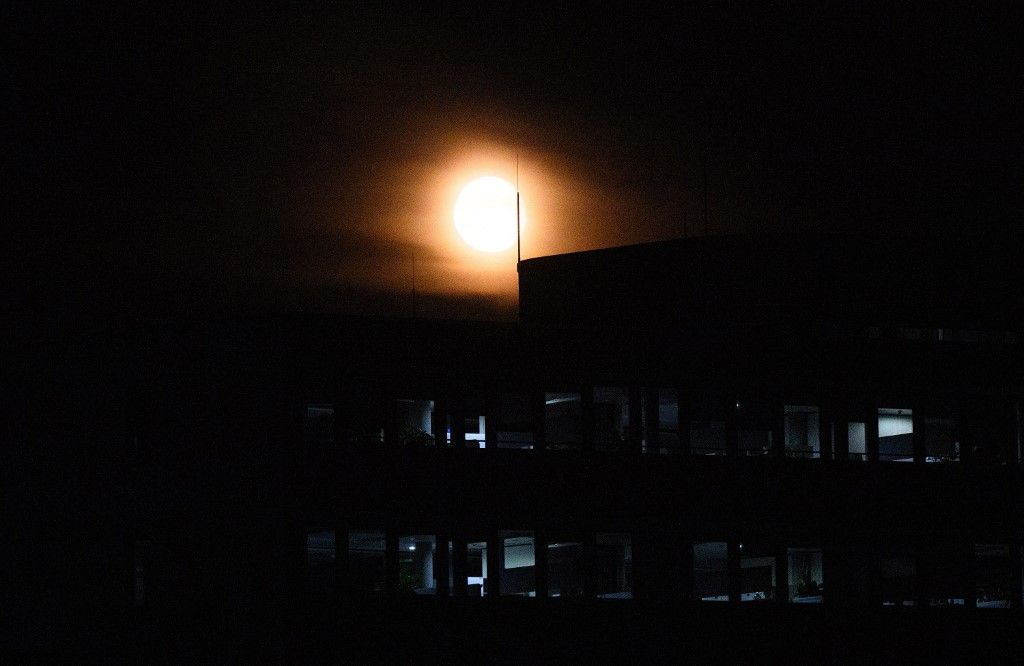 09 September 2025, Berlin: The moon shines over a poorly lit office building in Adlershof. Due to an arson attack on two electricity pylons, there was a widespread power outage in south-east Berlin. Around 43,000 households and 3,000 companies were initially affected. Repair work is continuing. Photo: Bernd von Jutrczenka/dpa (Photo by BERND VON JUTRCZENKA / dpa Picture-Alliance via AFP)