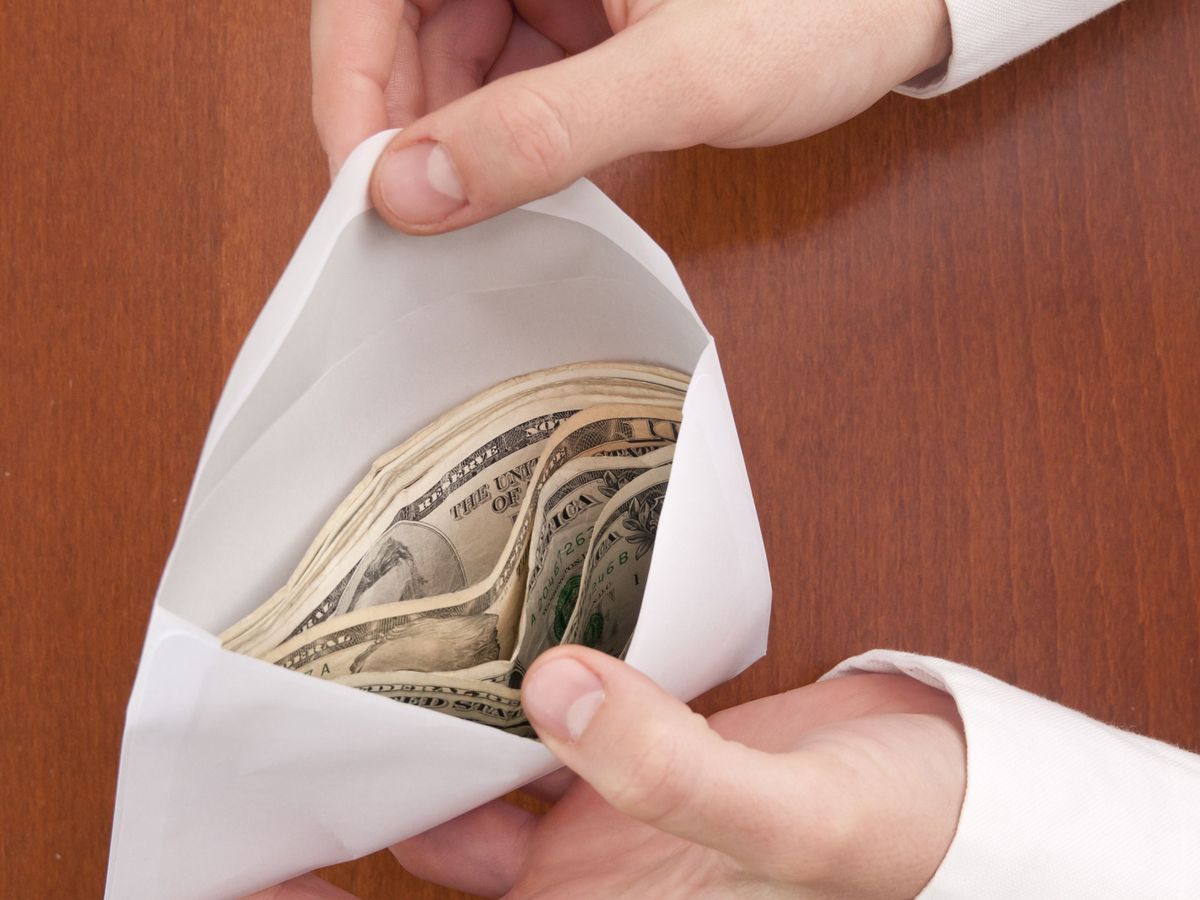 Corruption concept. Business man check a stack of money in envelope.