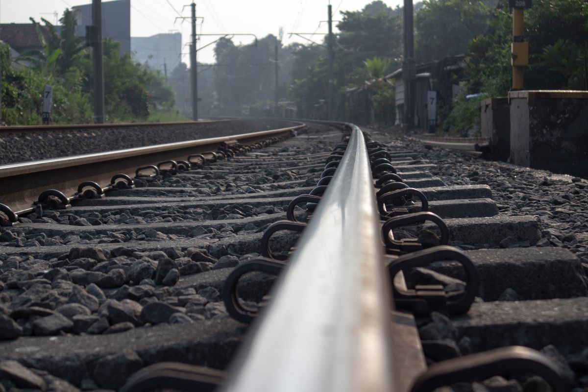 the railroad tracks on a hot day and look very shiny with rocks around the railroad tracks which are useful for dampening vibrations