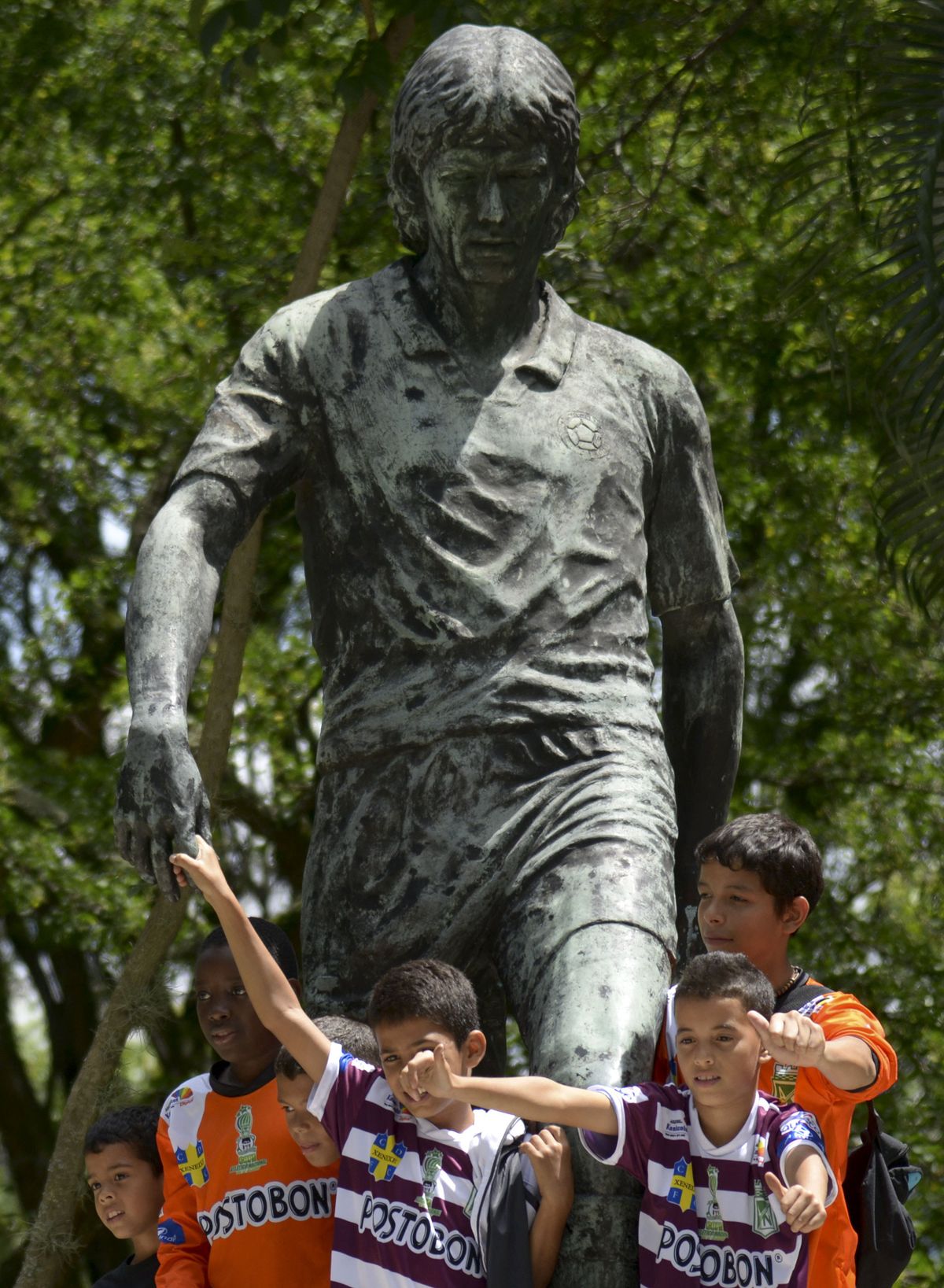 Supporters pose for  a picture before the monument to  late Colombian footballer Andres Escobar attend a ceremony in his honour in Medellin, Antioquia department, Colombia on July 2, 2014. Escobar was shot dead twenty years ago, upon the team's return from the FIFA World Cup in the United States where he had scored an own goal during the Colombia vs United States match. AFP PHOTO/Raul ARBOLEDA (Photo by RAUL ARBOLEDA / AFP)