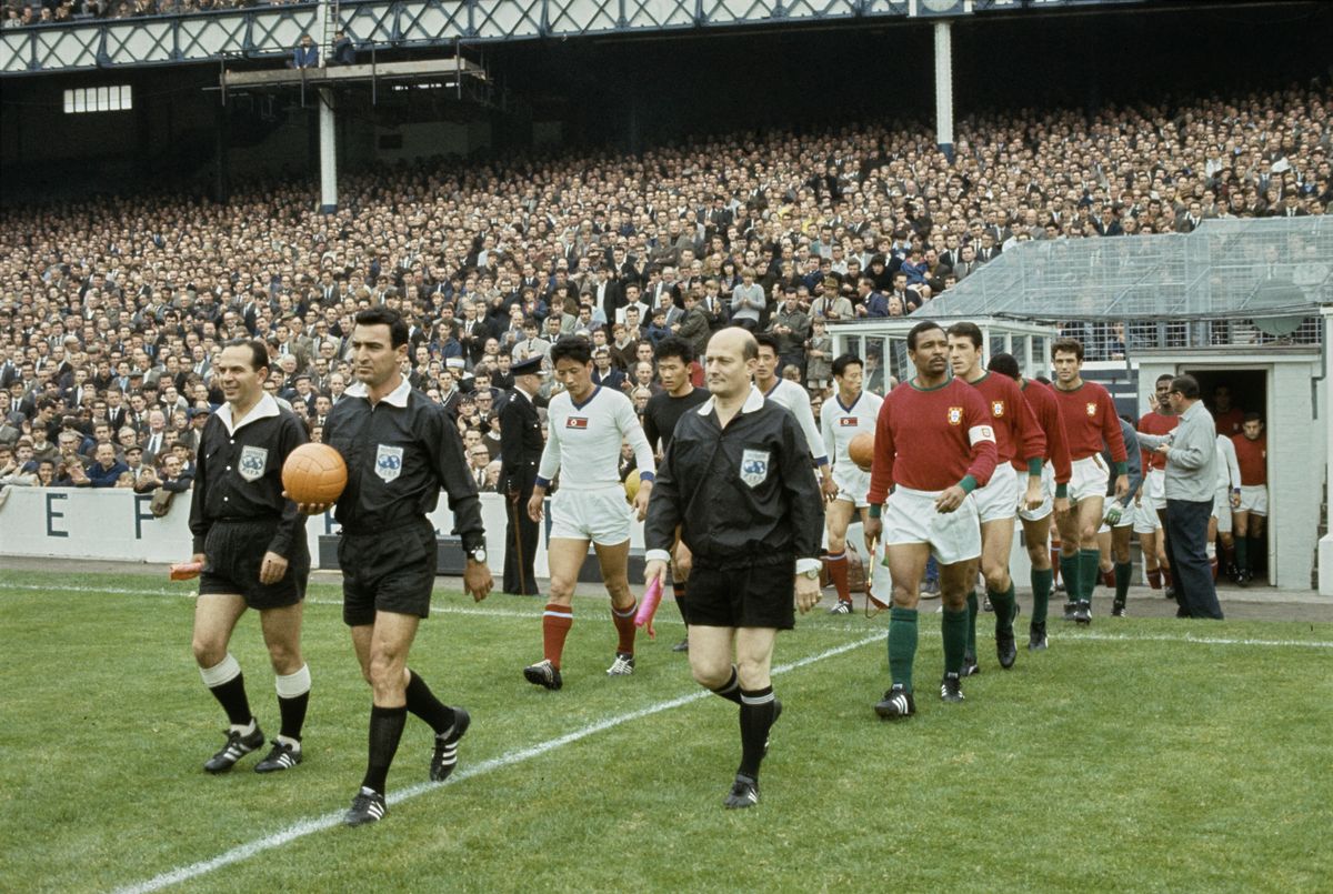 1966-os labdarúgó-világbajnokság
Észak-Korea Portugália mérkőzés

Captains Shin Yung Koo of North Korea and Mario Coluna of Portugal lead their teams onto the field at Goodison Park stadium for their World Cup quarter-finals match, Liverpool, England, July 23rd 1966. Walking ahead of them are referee Menachem Ashkenazi (Israel) with linesmen Pierre Schwinte (France) and Karol Galba (Czechoslovakia). (Photo by Central Press/Hulton Archive/Getty Images)