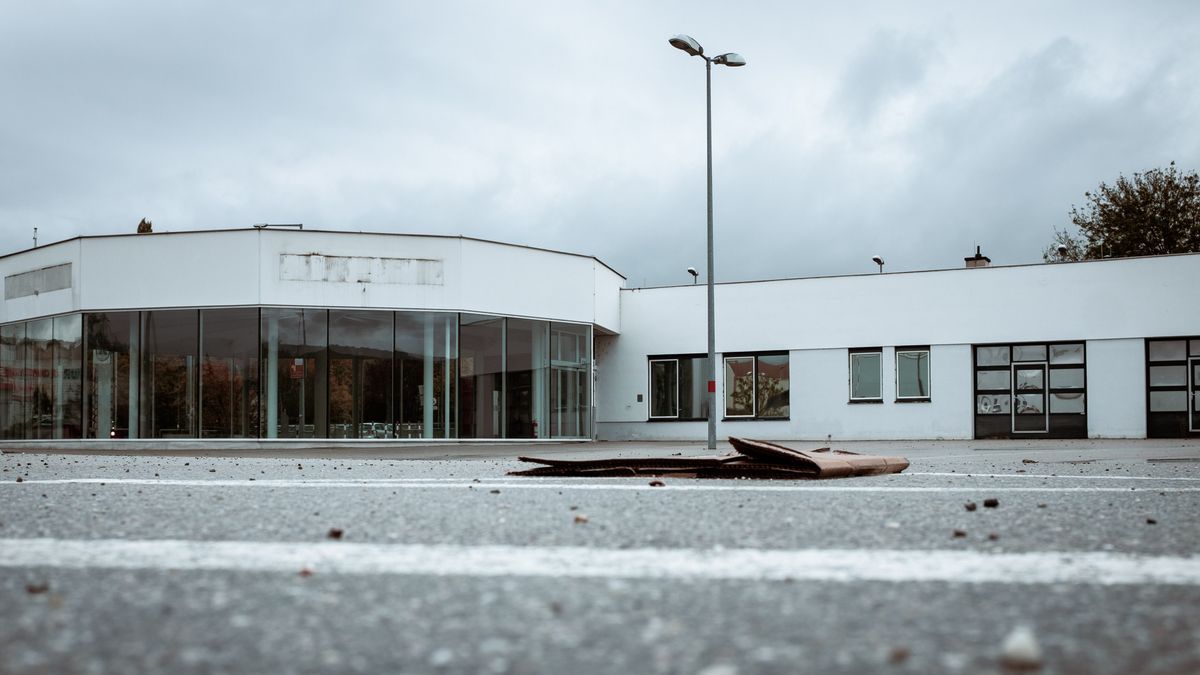Abandoned Car dealership during Corona pandemic. Local business going bankrupt. Old cardboard box in Foreground, entrance area in background. Dramatic autumn sky.