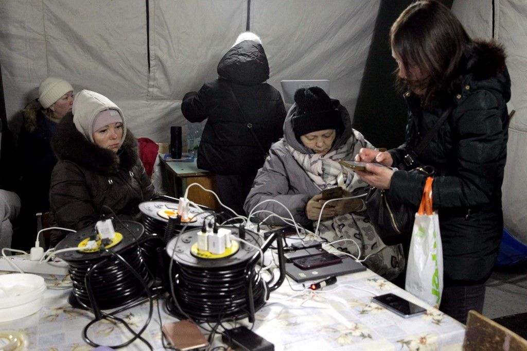 People charge mobile phones and power banks at a mobile heating point in the Desnianskyi district of Kyiv, Ukraine, on January 22, 2026. The heating point is deployed amid power and heating outages after Russian attacks on energy infrastructure (Photo by Hennadii Minchenko/Ukrinform/NurPhoto). NO USE RUSSIA. NO USE BELARUS. (Photo by Ukrinform/NurPhoto) (Photo by Hennadii Minchenko / NurPhoto via AFP)