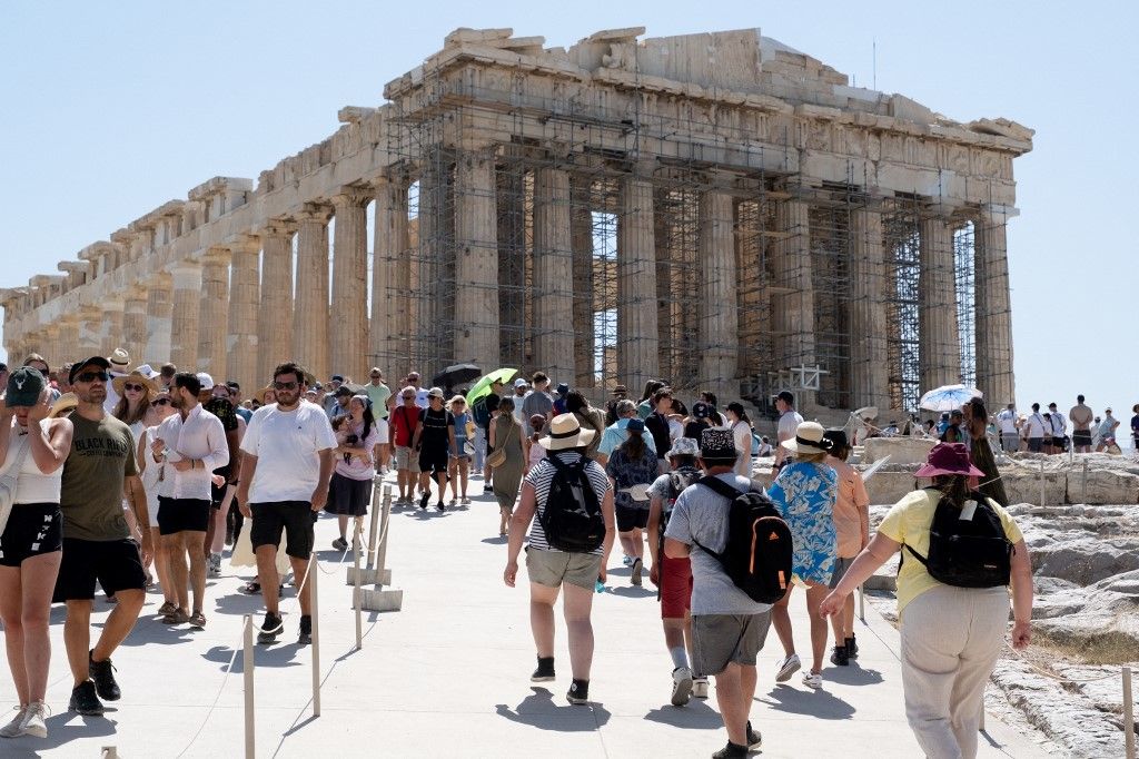 Thousands of tourists wear hats and carry umbrellas for protection as they visit the Acropolis during the worst heatwave of the season in Athens, Greece, on July 23, 2025. The Acropolis shuts between 12:00 and 17:00 to protect visitors and workers from the intense heat. (Photo by Nikolas Kokovlis/NurPhoto) (Photo by Nikolas Kokovlis / NurPhoto via AFP)