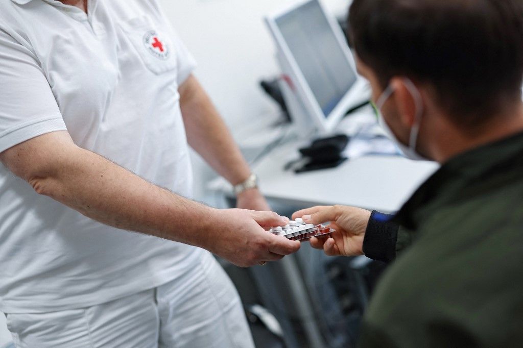 18 June 2024, Bavaria, Zirndorf: An employee of the German Red Cross gives medication to a migrant at the central reception center for asylum seekers in Bavaria. Photo: Daniel Löb/dpa (Photo by Daniel Löb / dpa Picture-Alliance via AFP)