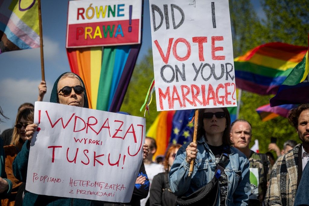 Participants wave rainbow flags and hold placards reading (from L) 'Tusk - Enforce The Ruling!', 'Equal Rights' and 'Did I vote on your marriage?' during a demonstration of LGBT organisations in Warsaw on April 25, 2026. The LGBT organisations point out that the Polish government has not implemented landmark rulings of the European Court of Human Rights that require Poland to recognize same-sex marriages concluded in other EU member states. (Photo by Wojtek RADWANSKI / AFP)