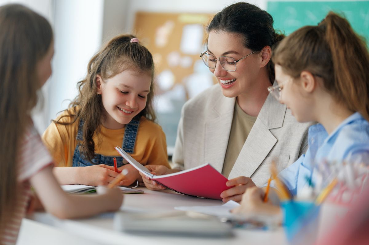 Happy kids and teacher at school. Woman and children are working in the class.