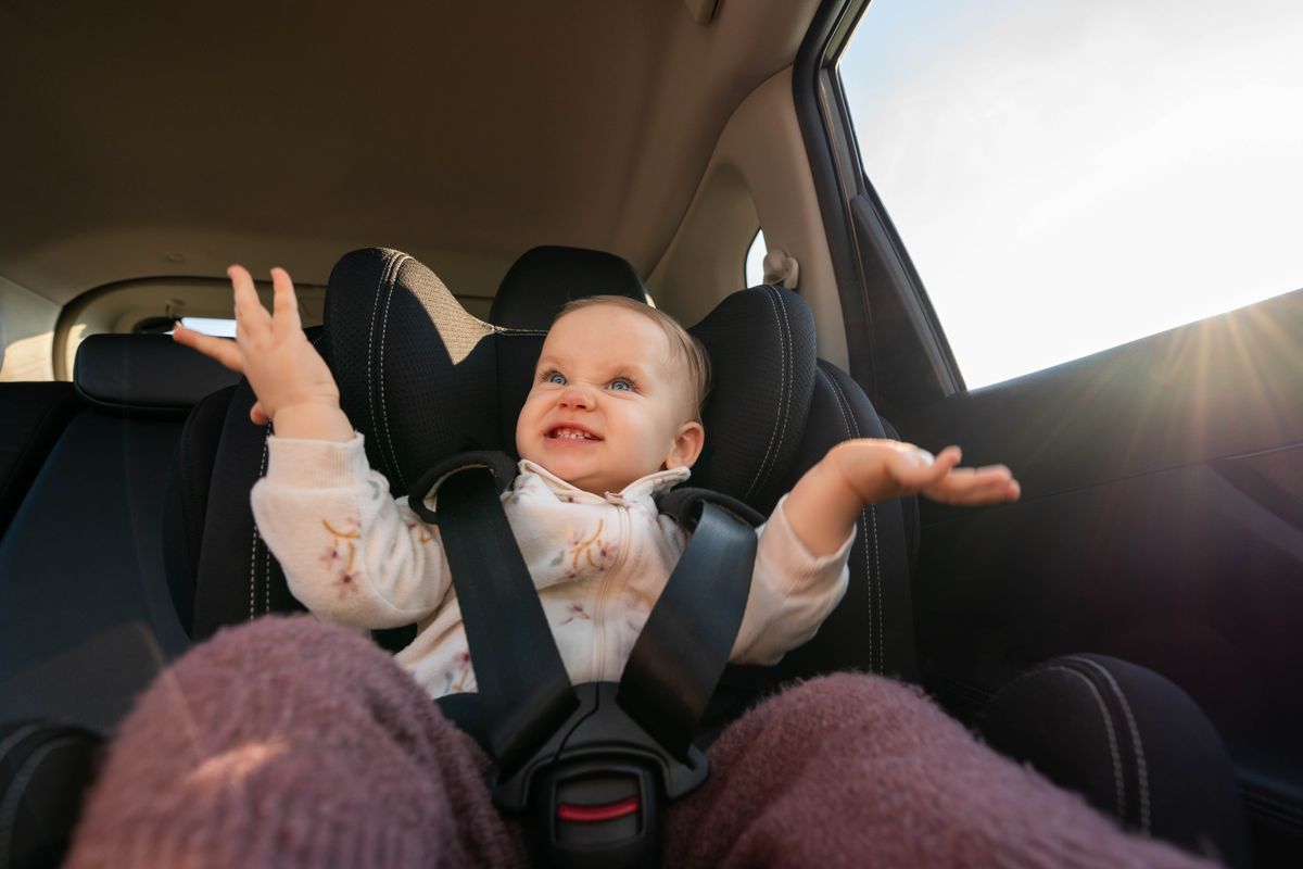 Happy baby clapping hands in car seat during family trip. Concept of safe travel and playful moments for young passengers