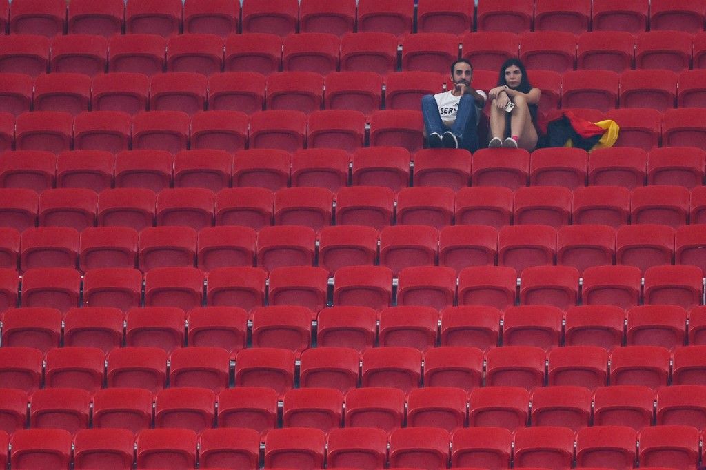 02 December 2022, Qatar, Al-Chaur: Soccer: World Cup, Costa Rica - Germany, preliminary round, Group E, Matchday 3, Al-Bait Stadium, two spectators sit next to the crumpled German flag in the empty stands after the end of the match. Photo: Tom Weller/dpa (Photo by Tom Weller / dpa Picture-Alliance via AFP)