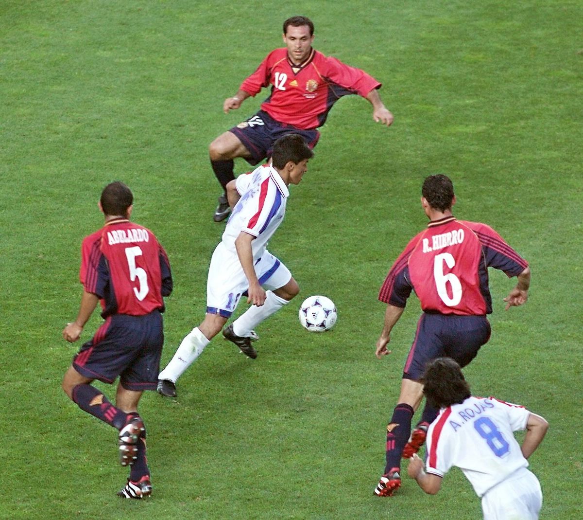 Paraguayan mid-fielder Miguel Benitez (C) is surrounded by Spanish players Abdelardo (#5), Sergi (#12) and Fernando Hierro (#6) while Paraguay's forward Aristides Rojas (#8) is looking on at Geoffroy Guichard stadium 19 June in Saint-Etienne, central France, during the 1998 Soccer World Cup Group D match between Spain and Paraguay. (ELECTRONIC IMAGE) (Photo by PASCAL GEORGE / AFP)