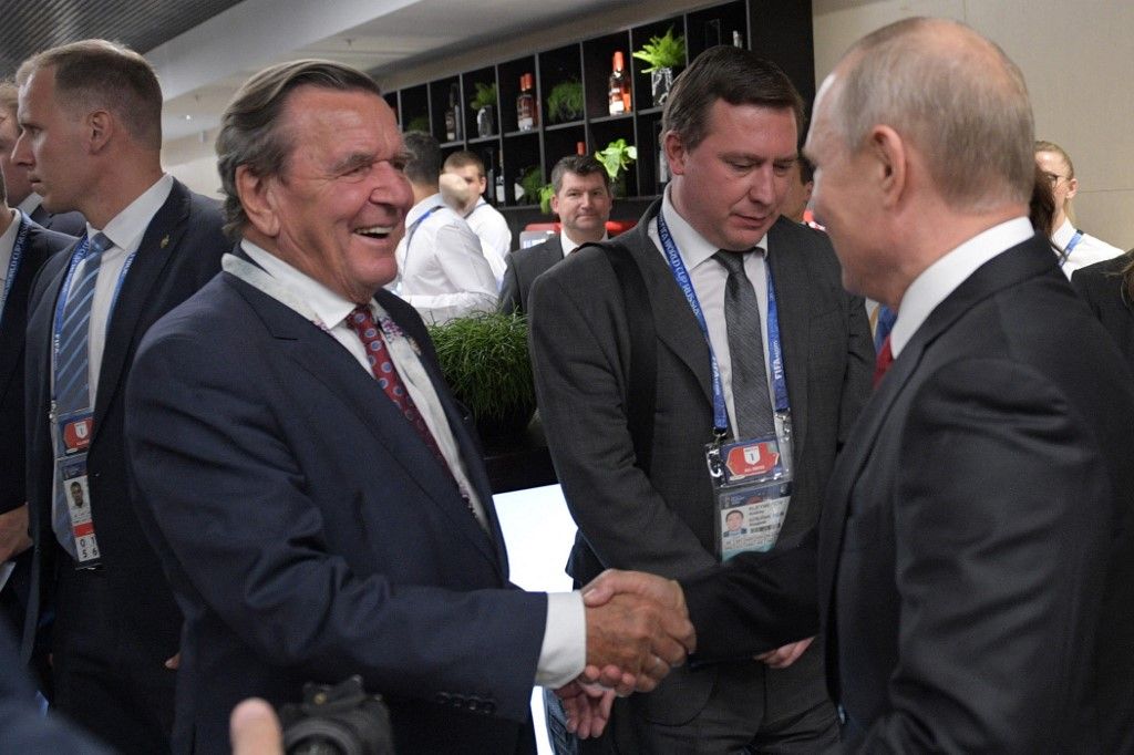Russian President Vladimir Putin (R) shakes hands with Germany's former chancellor Gerhard Schroeder at the half-time during the Russia 2018 World Cup Group A football match between Russia and Saudi Arabia at the Luzhniki Stadium in Moscow on June 14, 2018. (Photo by Alexey DRUZHININ / SPUTNIK / AFP)