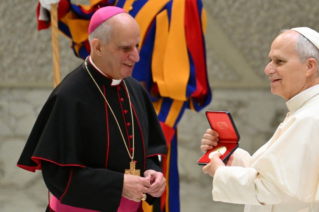Pope Leo XIV (R) receives a Jubilee medal from Bishop Rino Fisichella during his audience to the Collaborators and Volunteers of the Jubilee in the Paul VI hall at the Vatican on January 10, 2026. (Photo by Alberto PIZZOLI / AFP)