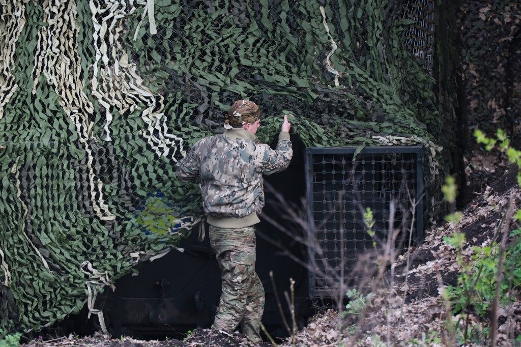 A soldier from the 13th Khartiia Operational Brigade of Ukraine's National Guard covers an M113 armored personnel carrier with a camouflage net in preparation for combat use as the brigade gears up for a rotation on April 16, 2026. Servicemen of the Khartiia Brigade are mastering new weapons and training for combat operations under the threat of Russian drones. (Photo by Viacheslav Madiievskyi/Ukrinform/NurPhoto) (Photo by Viacheslav Madiievskyi / NurPhoto via AFP)
