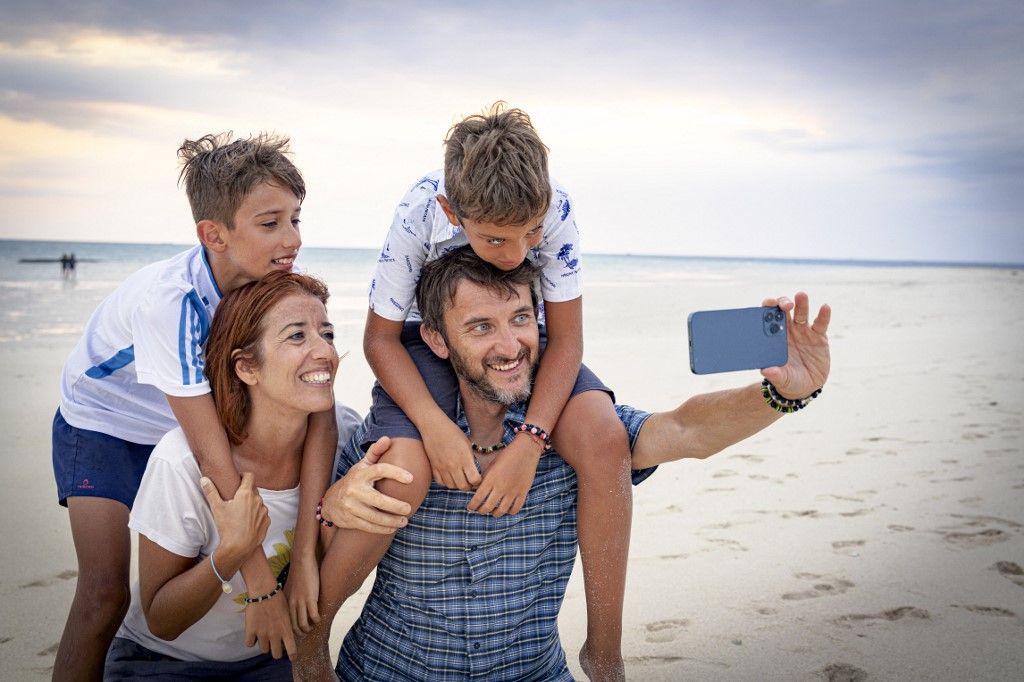 Happy family with two boys snapping a selfie with smartphone on a beach, Zanzibar, Tanzania, East Africa, Africa (Photo by Roberto Moiola / Robert Harding RF / robertharding via AFP)