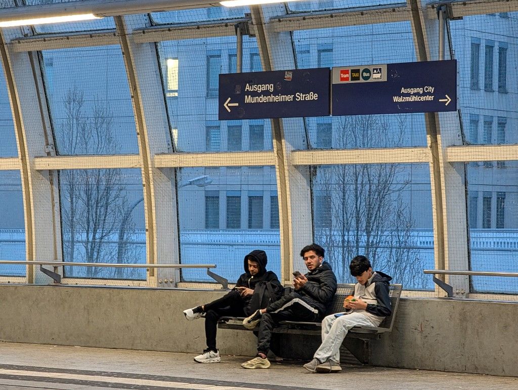 Three young men use smartphones while waiting on the platform at Ludwigshafen Mitte station in Ludwigshafen am Rhein, Rhineland-Palatinate, Germany, on April 4, 2026. The station is part of the Rhine-Neckar regional and S-Bahn rail network connecting Ludwigshafen with Mannheim and other destinations in the region. (Photo by Michael Nguyen/NurPhoto) (Photo by Michael Nguyen / NurPhoto via AFP)