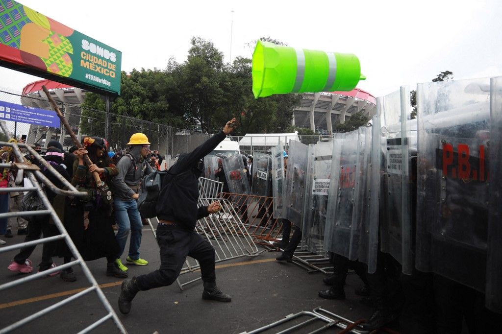 MEXICO CITY, MEXICO - JUNE 11: A protester throws a plastic warning cone at the police as demonstrators clash with riot police near Banorte Stadium during the World Cup opener, in Mexico City, Mexico on June 11, 2026. Thousands of demonstrators marched toward Banorte Stadium to protest against the World Cup, while some clashed with riot police outside the stadium where the World Cup opener was taking place. Daniel Cardenas / Anadolu (Photo by Daniel Cardenas / Anadolu via AFP)