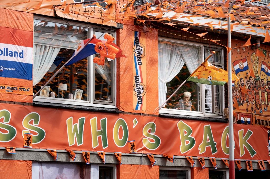 An ederly woman looks through a window in the Marktweg street, decorated and renamed "Oranjestraat" (orange street) by its residents during the 2026 FIFA World Cup football tournament in The Hague on June 12, 2026. The Netherlands will open its 2026 FIFA World Cup Group F campaign co-hosted by the United States, Mexico and Canada, against Japan at the AT&T Stadium in Arlington on June 14, 2026. (Photo by Lina Selg / AFP)