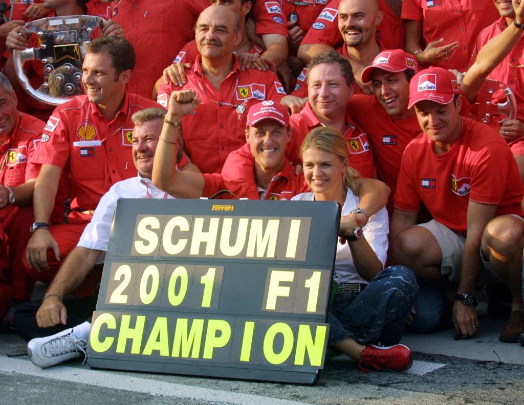 German Ferrari driver Michael Schumacher shows his scoreboard of World Champion next to his wife Corinna and with all the Ferrari team in the pits of the Hungaroring racetrack near Budapest, 19 August 2001, at the end of the Hungarian Formula One Grand Prix. Schumacher won the race ahead of his teammate Rubens Barrichello and Scottish McLaren-Mercedes driver David Coulthard. Schumacher obtains his second successive world Champion tiltle. (Photo by PIERRE VERDY / AFP)