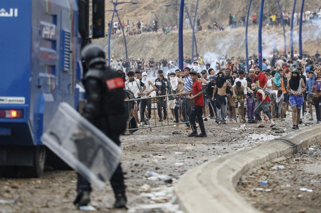 Moroccan security forces clash with migrants attempting to cross into Spain's North African enclave of Ceuta near the town of Fnideq, on the Morocco-Spain border, on July 31, 2026. The European Union on July 31 scrambled to contain one of the largest migrant crises faced by the block in recent years, after tens of thousands of people poured into into Spain's North African Ceuta enclave in just days. (Photo by Abdel Majid BZIOUAT / AFP)