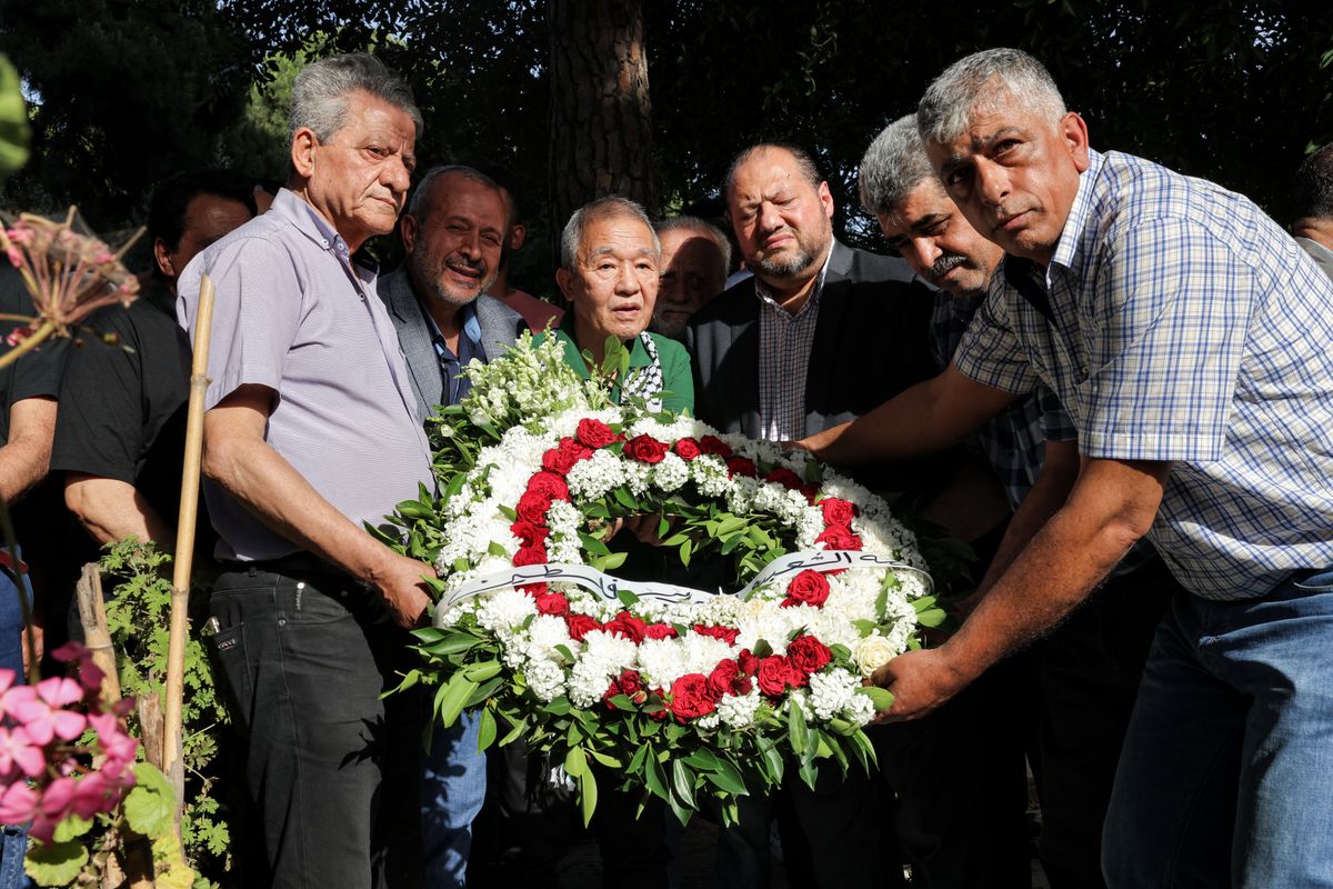 Kozo Okamoto (C) -- the only surviving member of the three-man "Japanese Red Army" (JRA) commando unit that killed 26 people in an attack on Israel's Lod airport on May 30, 1972 -- is assisted as he lays a wreath of flowers on a memorial dedicated to the others who carried out the Lod attack during a ceremony organised by Palestinian militants to mark its 50th anniversary, in Lebanon's capital Beirut on May 30, 2022. Palestinian militants in Beirut on May 30 marked the 50th anniversary of a deadly attack carried out by members of the Japanese Red Army at Israel's Lod airport. Kozo Okamoto, the only surviving member of the three-man commando that killed 26 people (including 17 Christian pilgrims from Puerto Rico) on May 30, 1972, made a rare appearance at the ceremony. The attack was planned by the Popular Front for the Liberation of Palestine (PFLP), which has commemorated it every year for a half a century. (Photo by JOSEPH EID / AFP)