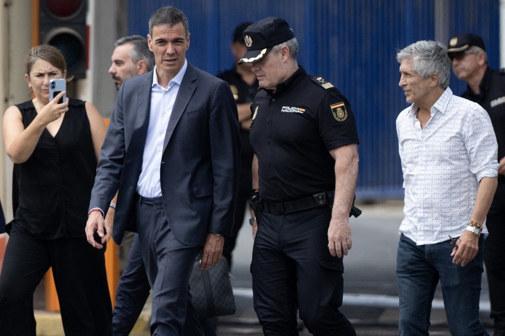 Spain's Prime minister Pedro Sanchez (C) and Minister of Interior Fernando Grande Marlaska (R) walk by the Tarajal border fence between Spain's north Africa's Ceuta enclave and Morocco during a visit to manage one the largest migrant crisis on the country's border as thousands of migrants crossed overnight from Morocco on July 31, 2026. In recent days, a total of around 40,000 migrants have crossed into the territory, a police source said, many swimming around the small border barrier that meets with the Mediterranean sea. The sudden massive influx has sparked an international crisis for Spain's government, drawing criticism from Italy and Finland and prompting France to tighten checks on its border with Spain. (Photo by JORGE GUERRERO / AFP)