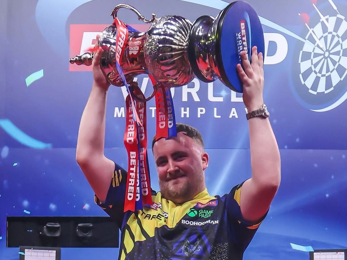 Az angol dartsjátékos, Luke Littler boldogan pózolt a Phil Taylor-trófeával a Gerwyn Price elleni World Matchplay-döntő után