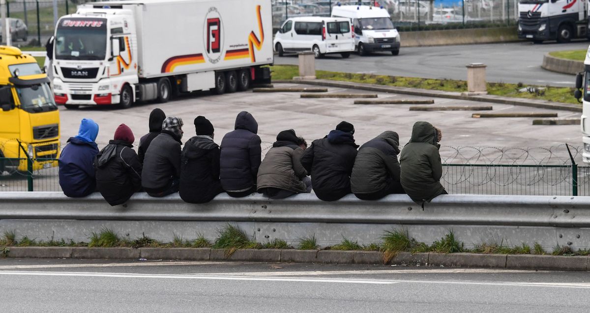 Migrants sit on a crash barrier overlooking a truck parking lot, by the ringroad leading to the harbour on March 30, 2018 in Calais. (Photo by Denis Charlet / AFP)