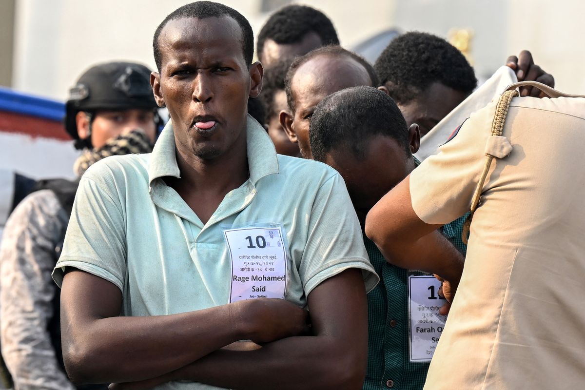 An accused Somali pirate gestures as he waits to be transferred to police custody at the Indian naval dockyard in Mumbai on March 23, 2024. India brought 35 accused Somali pirates to Mumbai on March 23, days after they were apprehended when naval commandos recaptured a hijacked bulk carrier and rescued several hostages. (Photo by Indranil MUKHERJEE / AFP)