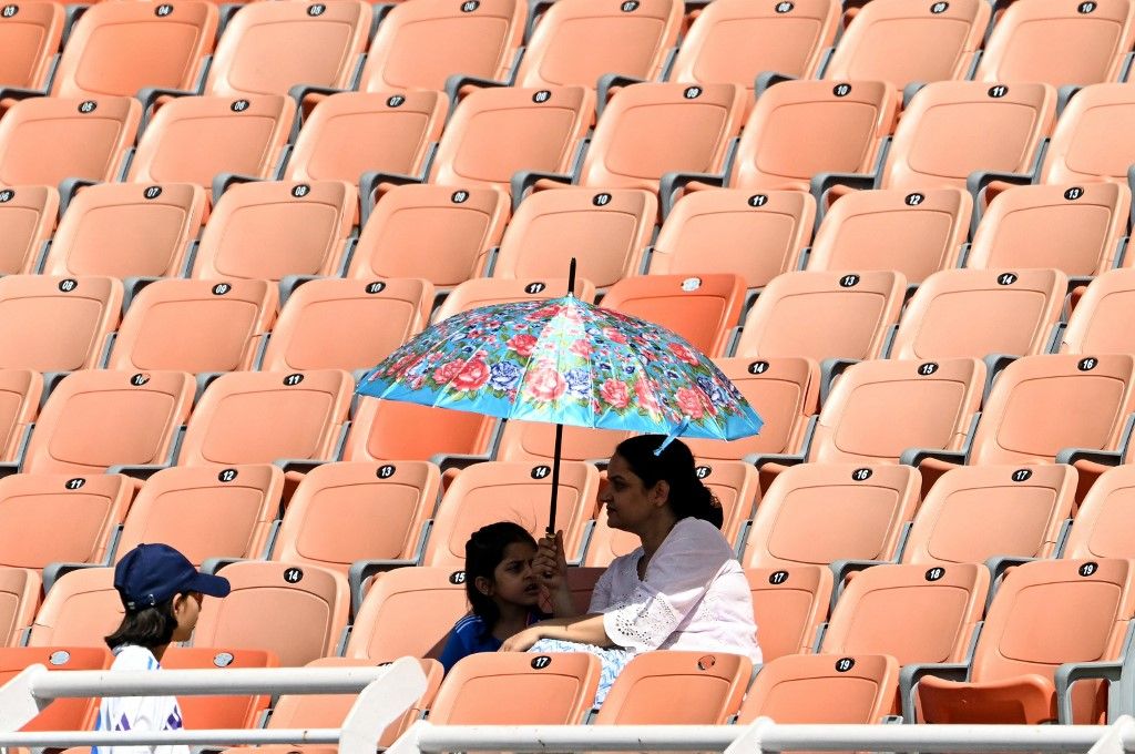 Spectators take shade under umbrellas during the first day of the only Test cricket match between India and Afghanistan at the Maharaja Yadavindra Singh International Cricket Stadium on the outskirts of Chandigarh on June 6, 2026. (Photo by Shammi MEHRA / AFP) / -- IMAGE RESTRICTED TO EDITORIAL USE - STRICTLY NO COMMERCIAL USE --