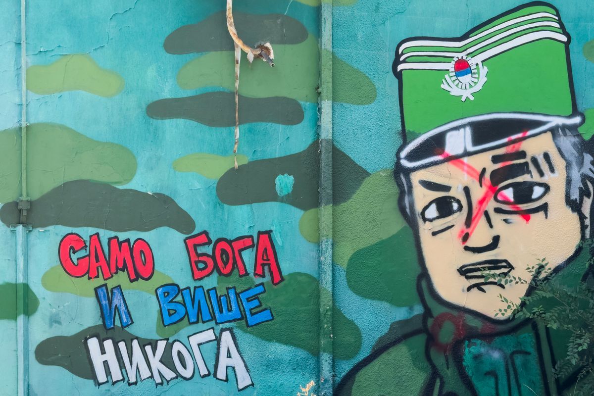 This photograph shows a defaced mural depicting former Bosnian Serb military chief Ratko Mladic, with a Cyrillic inscription (L) reading "Only God and no one else" in Belgrade on August 27, 2026. Ratko Mladic, the former Bosnian Serb military chief dubbed the "Butcher of Bosnia" for his role in the 1995 Srebrenica massacre, has died, Serbian state broadcaster RTS reported on August 27, 2026. (Photo by Andrej ISAKOVIC / AFP)