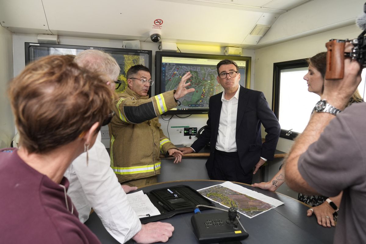 Britain's Prime Minister Andy Burnham listens to Chief Fire Officer Simon Tuhill (C) as he meets with emergency responders at the West Midlands Fire Service incident command unit, during a series of wildfires, in Stourbridge, central England on August 14, 2026. Firefighters continued Friday to extinguish wildfires that began on August 13, tearing through several homes, with residents evacuated and "extensive" damage reported. (Photo by Peter Byrne / POOL / AFP)