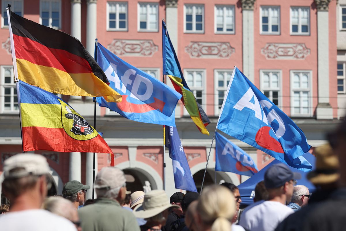 11 July 2026, Mecklenburg-Western Pomerania, Rostock: Participants in an AfD rally under the slogan "Stop Left-Wing Violence!" are holding a flag featuring the historic colors of Mecklenburg, German flags, and flags bearing the AfD logo at the Neuer Markt. Photo: Danny Gohlke/dpa (Photo by DANNY GOHLKE / dpa Picture-Alliance via AFP)