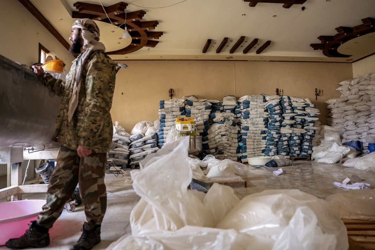 A Syrian rebel fighter inspects a makeshift lab facility to produce Captagon (brand name of psychostimulant drug Fenethylline), at a ranch villa in the town of al-Dimas about 27 kilometres northwest of Damascus on December 22, 2024. The dramatic collapse of Bashar al-Assad's Syrian regime has thrown light into many of the dark corners of his rule, including the industrial-scale export of the banned drug Captagon. Victorious Islamist fighters have seized military bases and distribution hubs for the amphetamine-laced stimulant, which has flooded the black market across the Middle East. (Photo by OMAR HAJ KADOUR / AFP)