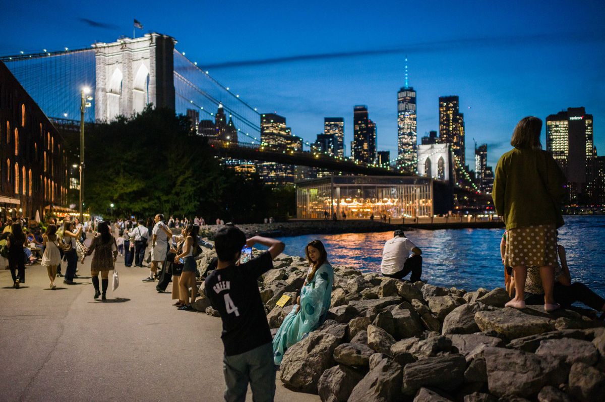 NEW YORK, NEW YORK - SEPTEMBER 8: People take photographs in front of the Brooklyn Bridge, One World Trade Center and Lower Manhattan skyline on September 8, 2026 in the Brooklyn borough of New York City. The Tribute In Light art installation will be able to be seen within a 60-mile radius around Lower Manhattan from dusk on September 11 to dawn on September 12. Adam Gray/Getty Images/AFP (Photo by Adam Gray / GETTY IMAGES NORTH AMERICA / Getty Images via AFP)