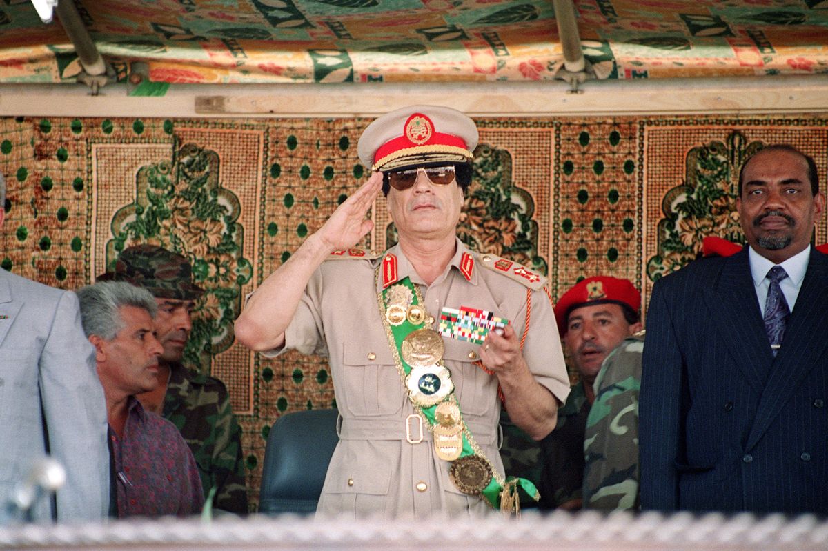 Libyan leader colonel Moamar Kadhafi (C), salutes troops during a military parade 01 September 1994 in Tripoli for the celebration of the 25th anniversary of Gadhafi's arrival in power. Kadhafi led a bloodless coup in 1969, that ousted King Idriss while the monarch was out of the country. Standing at right, is Sudanese General leader Omar Al-Bashir. (Photo by MANOOCHER DEGHATI / ARCHIVES / AFP)