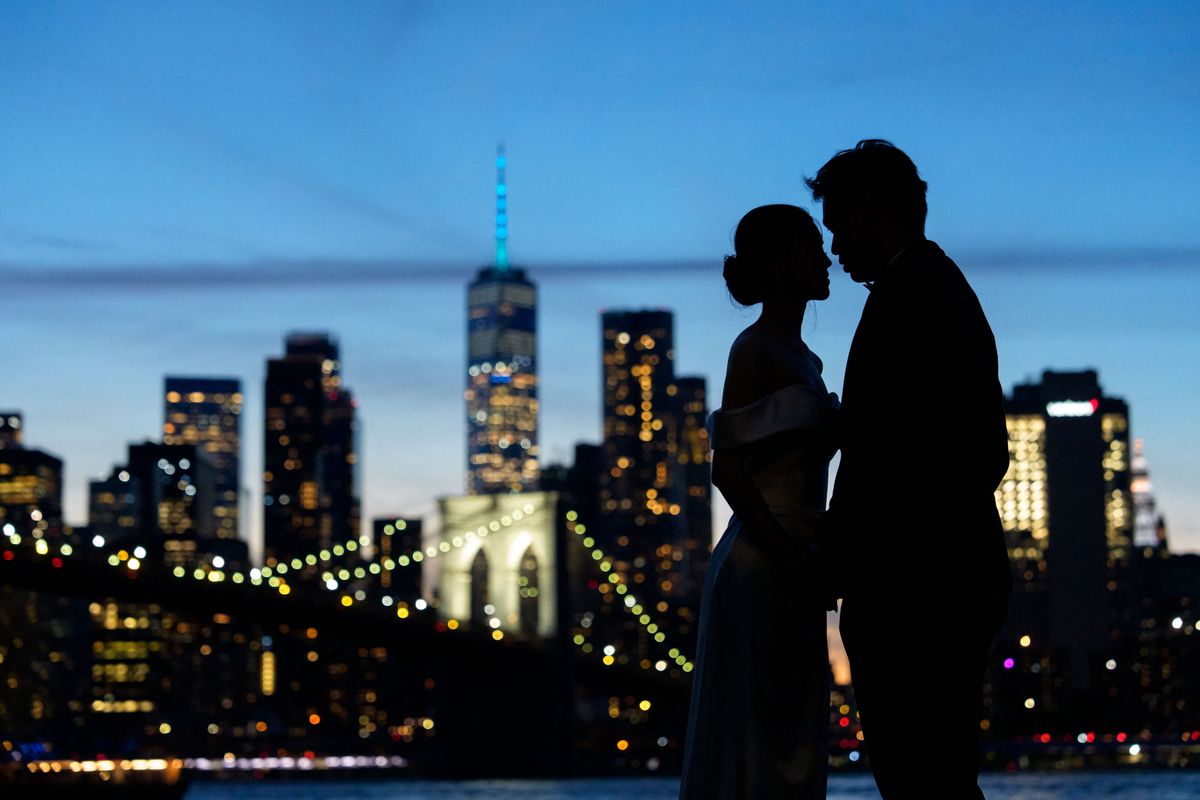 NEW YORK, NEW YORK - SEPTEMBER 8: A bride and groom pose for photographs in front of the Brooklyn Bridge, One World Trade Center and Lower Manhattan skyline on September 8, 2026 in the Brooklyn borough of New York City. The Tribute In Light art installation will be able to be seen within a 60-mile radius around Lower Manhattan from dusk on September 11 to dawn on September 12. Adam Gray/Getty Images/AFP (Photo by Adam Gray / GETTY IMAGES NORTH AMERICA / Getty Images via AFP)