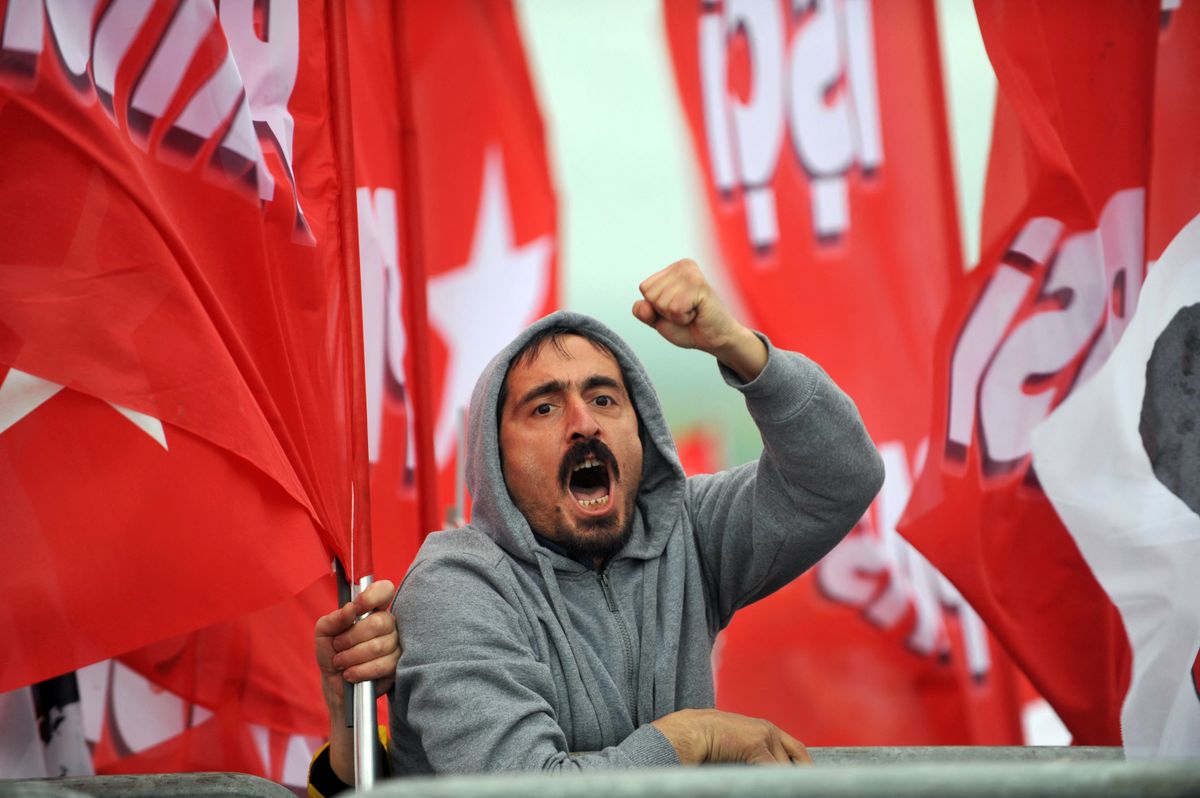 A man chants slogans out of a courthouse as Turkish gendarmerie block the road in Silivri near Istanbul on April 8, 2013 where prosecutors are scheduled to deliver their final arguments in the case against 275 people accused of plotting to overturn the Islamic-leaning government. A verdict in the four-year long case involving 275 defendants, including Turkey's former military chief Ilker Basbug and other army officers as well as lawyers, academics and journalists, is expected in the coming weeks. The defendants face dozens of charges, ranging from membership in an underground "terrorist organisation" known as Ergenekon and instigating an armed uprising against Erdogan and his Justice and Development Party (AKP), which came to power in 2002. AFP PHOTO/OZAN KOSE (Photo by OZAN KOSE / AFP)
