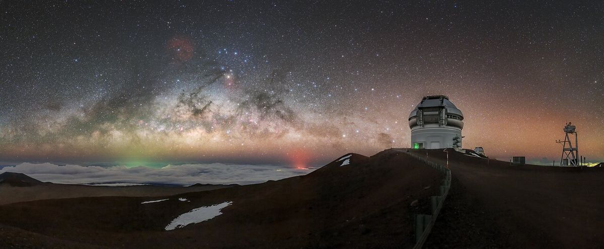 There’s more going on in this picture than you might think. This image shows Gemini North, located on Maunakea in Hawai‘i. Gemini North is one half of the International Gemini Observatory, a Program of NSF NOIRLab. To the lower left of Gemini is a red glowing light source. This is from the eruption of the Halemaʻumaʻu crater of the Kīlauea volcano, ongoing since late September 2021. Further lower left of Gemini is the faint green light of Hilo, Hawai‘i, mostly hidden by the layer of clouds that often covers the ground as seen from Maunakea. This is a form of light pollution, caused by excessive light shining up into the night sky above. However, protected by the high altitude, Gemini North is frequently shielded by a thick blanket of cloud. This barrier obscures urban light pollution and ambient natural light coming from the island and ocean below. This photo was taken as part of the recent NOIRLab 2022 Photo Expedition to all the NOIRLab sites.
