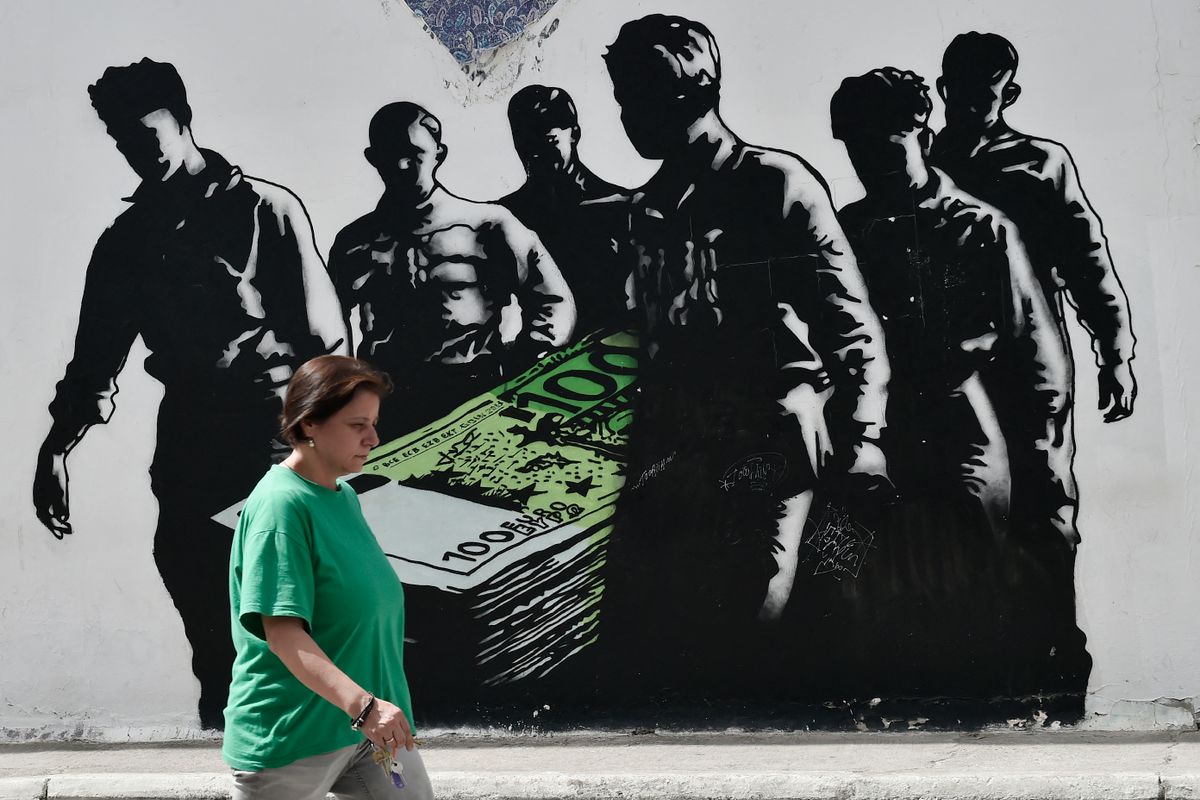 A woman walks past graffiti in the Greek capital Athens by French street artist Goin on July 25, 2017. Greece will make its first return to the debt markets in three years on July 25, 2017 , testing the waters to see if it can begin to wean itself off bailout loans after tough reforms. (Photo by LOUISA GOULIAMAKI / AFP) / RESTRICTED TO EDITORIAL USE - MANDATORY MENTION OF THE ARTIST UPON PUBLICATION - TO ILLUSTRATE THE EVENT AS SPECIFIED IN THE CAPTION